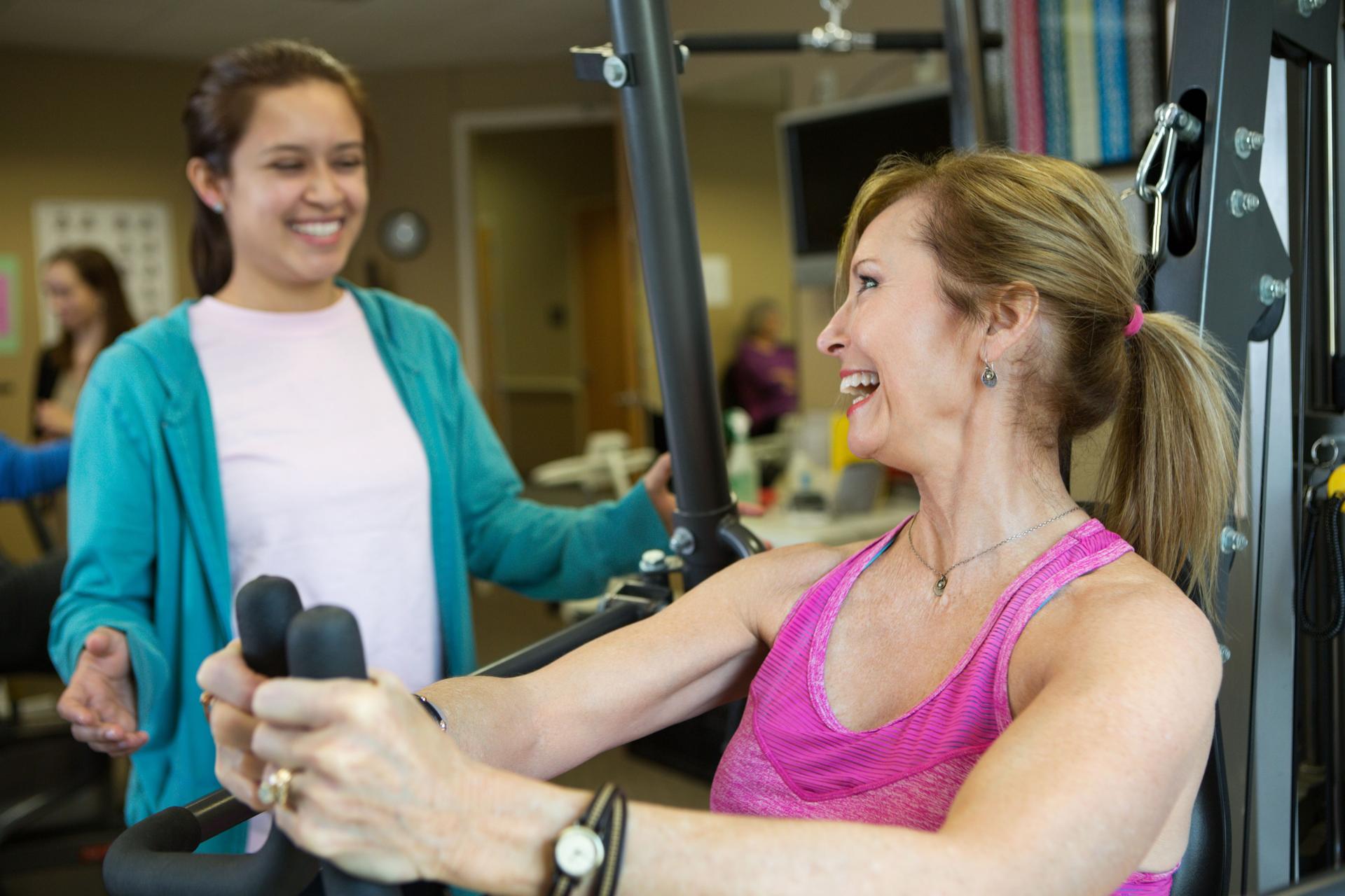 Personal trainer with client on weight machine